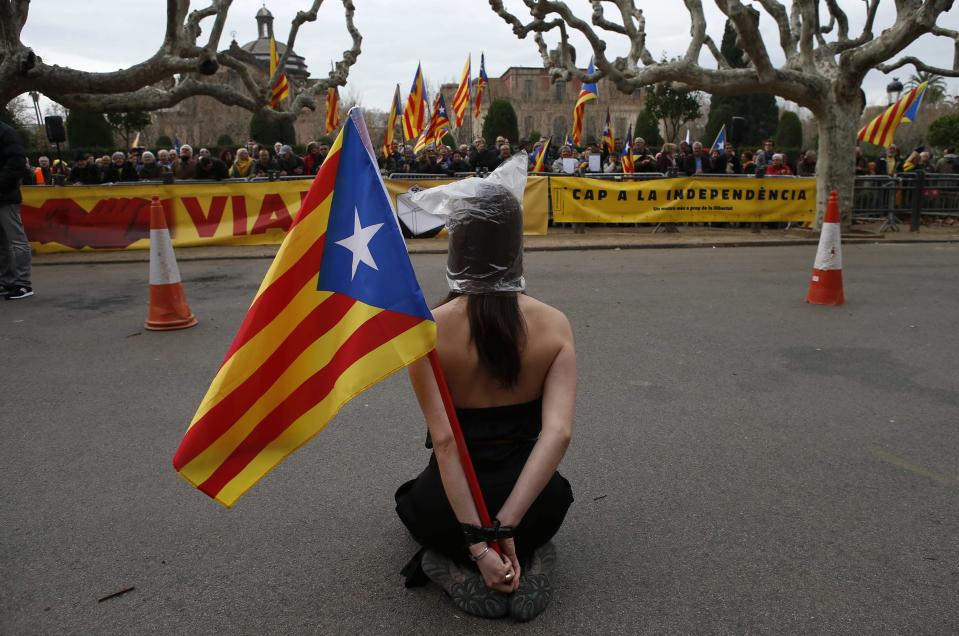 A pro-independence protestor sits in front of other demonstrators next to Catalonia's regional parliament as lawmakers voted inside, in Barcelona,