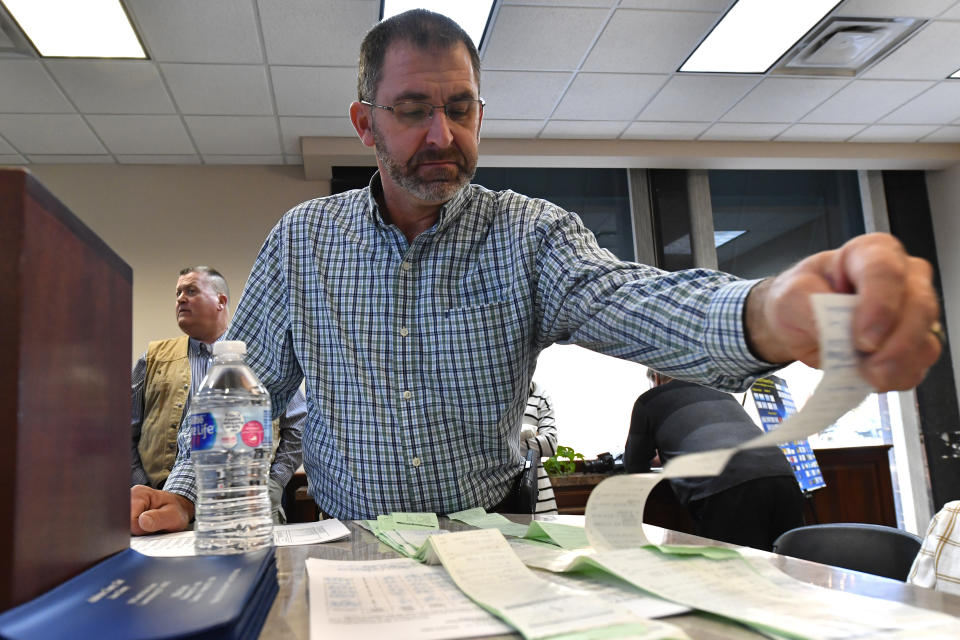 Anderson County Clerk Jason Denny looks over the printouts from the voting machines during the remcanvass of the results from the election for Kentucky Governor in Lawrenceburg, Ky., Thursday, Nov. 14, 2019. Election officials across Kentucky have started double-checking vote totals that show Republican Gov. Matt Bevin trailing Democrat Andy Beshear by more than 5,000 votes. (AP Photo/Timothy D. Easley)