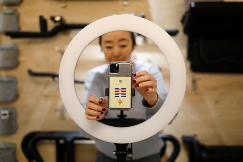 Liu Xiaojin, sets a phone as she gets ready to livestream a gym class, as the country is hit by an outbreak of the new coronavirus, in Beijing