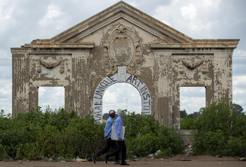 FILE - In this Feb. 15, 2021, young men walk back from school, passing the remains of the original Residensia Magistrate's Court building, built in 1937, in Evaton, south of Johannesburg, South Africa. A survey of people aged 18-24 in 15 African countries found that many have lost jobs or have seen their education disrupted by the pandemic. (AP Photo/Themba Hadebe, File)
