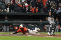 Baltimore Orioles' Colton Cowser, left, scores in extra innings during a baseball game against the Arizona Diamondbacks, Saturday, May 11, 2024, in Baltimore. (AP Photo/Jose Luis Magana)