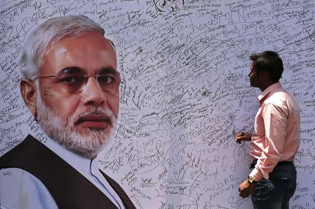 A man prepares to sign on a signature board with a picture of Hindu nationalist Narendra Modi, the prime ministerial candidate for the Bharatiya Janata Party (BJP), installed at the BJP headquarters in New Delhi May 16, 2014. REUTERS/Adnan Abidi