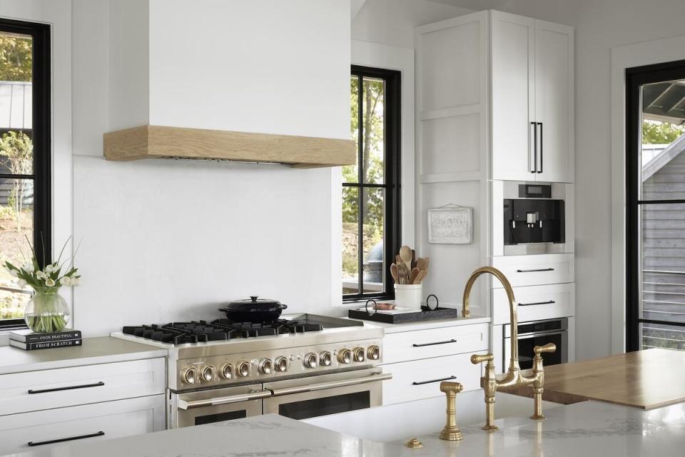 A sleek white kitchen features black and brass accents