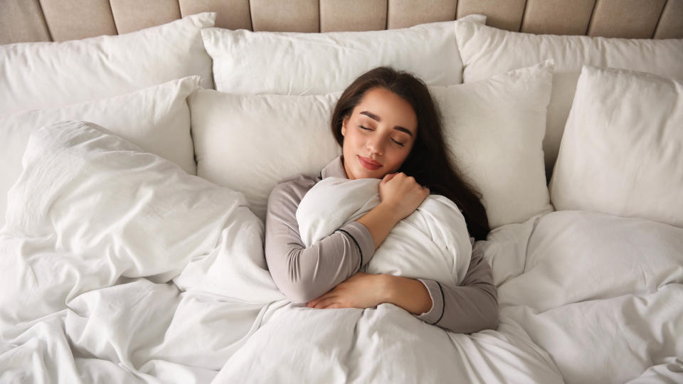 A woman in bed hugging the comforter