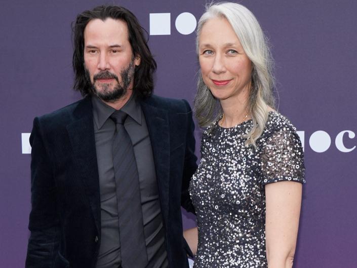 Keanu Reeves, in a black suit, and Alexandra Grant, in a sparkly gunmetal dress, pose for a photo together on the red carpet at the 2019 Benefit for the Museum of Contemporary Art in Los Angeles.