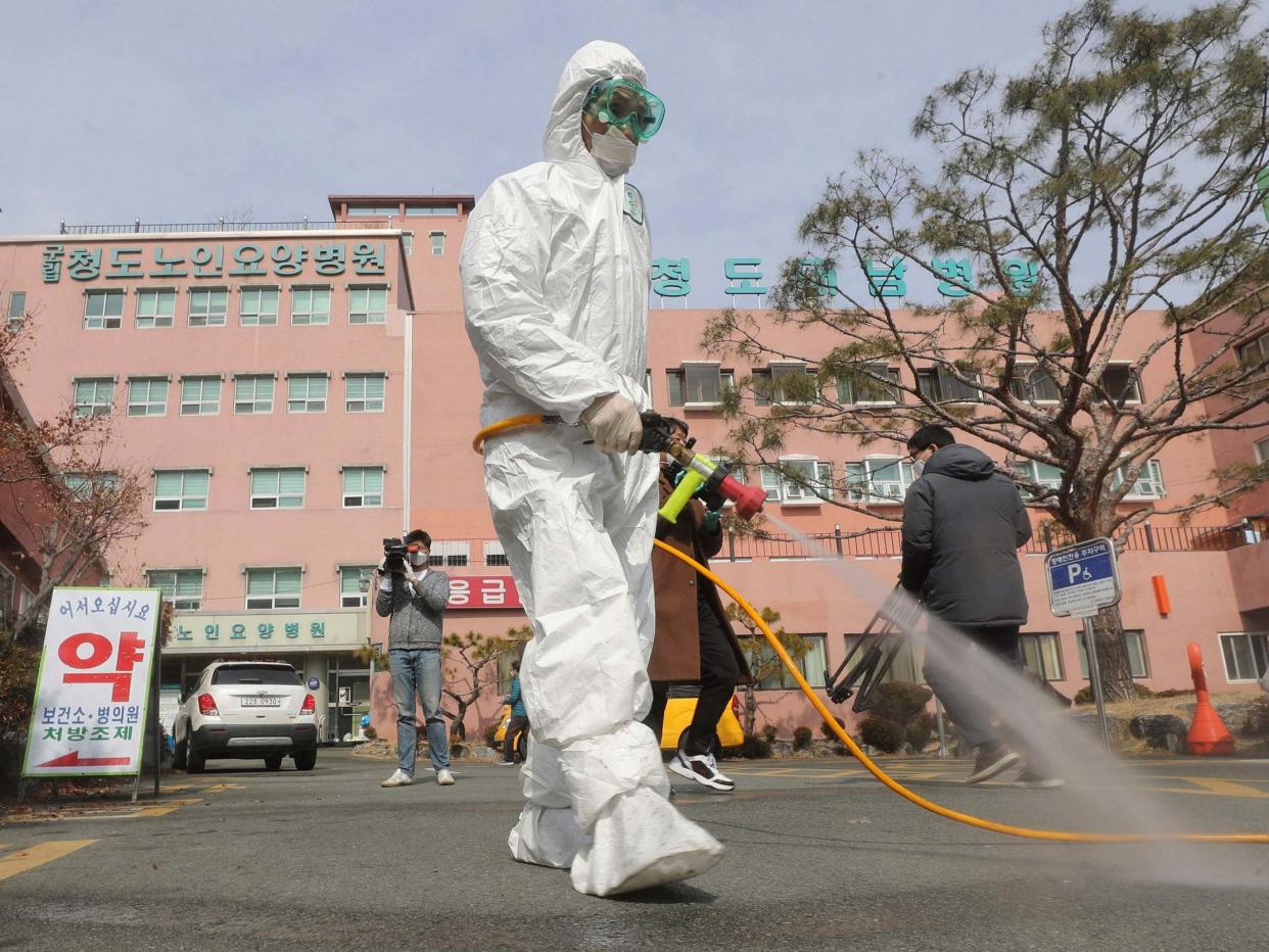 A worker wearing protective gears sprays disinfectant against the coronavirus in front of the Daenam Hospital in Cheongdo, where a 'special care zone' has been declared: Lim Hwa-young/Yonhap via AP