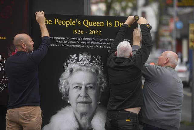 Council workers and local community representatives hang a mural on a wall on Crimea Street off the Shankill Road in Belfast 