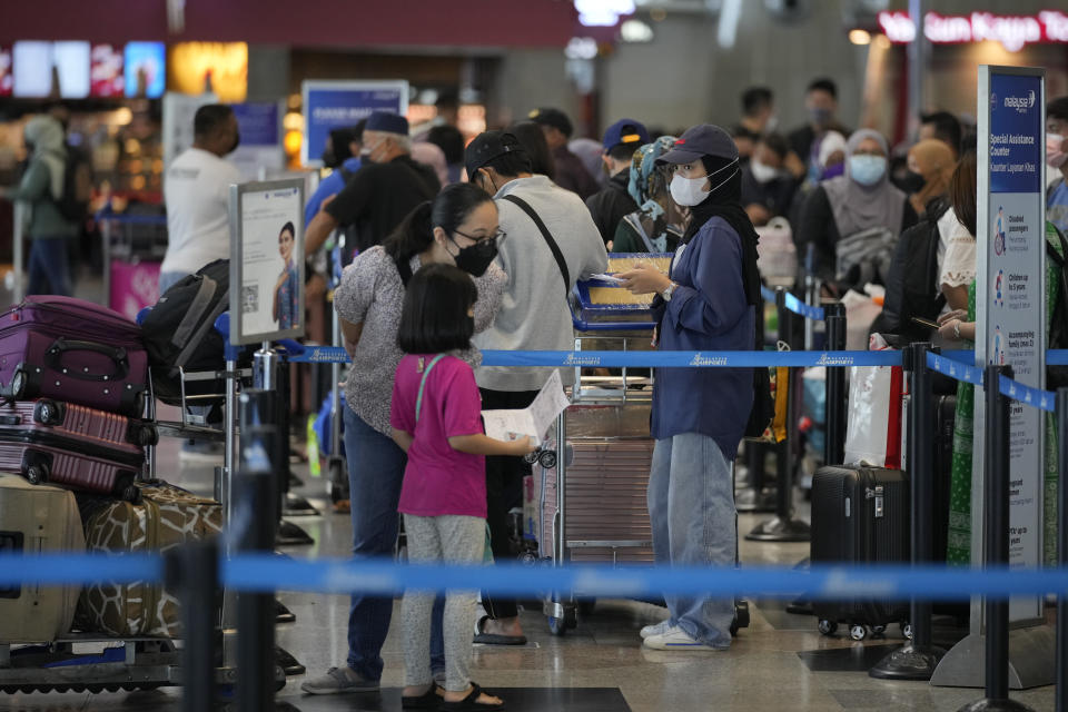 Travelers line up at check in counter at Kuala Lumpur International Airport in Sepang, Malaysia, Friday, April 1, 2022. Malaysia's international borders open to foreigners on Friday and fully vaccinated travelers do not have to undergo quarantine. (AP Photo/Vincent Thian)