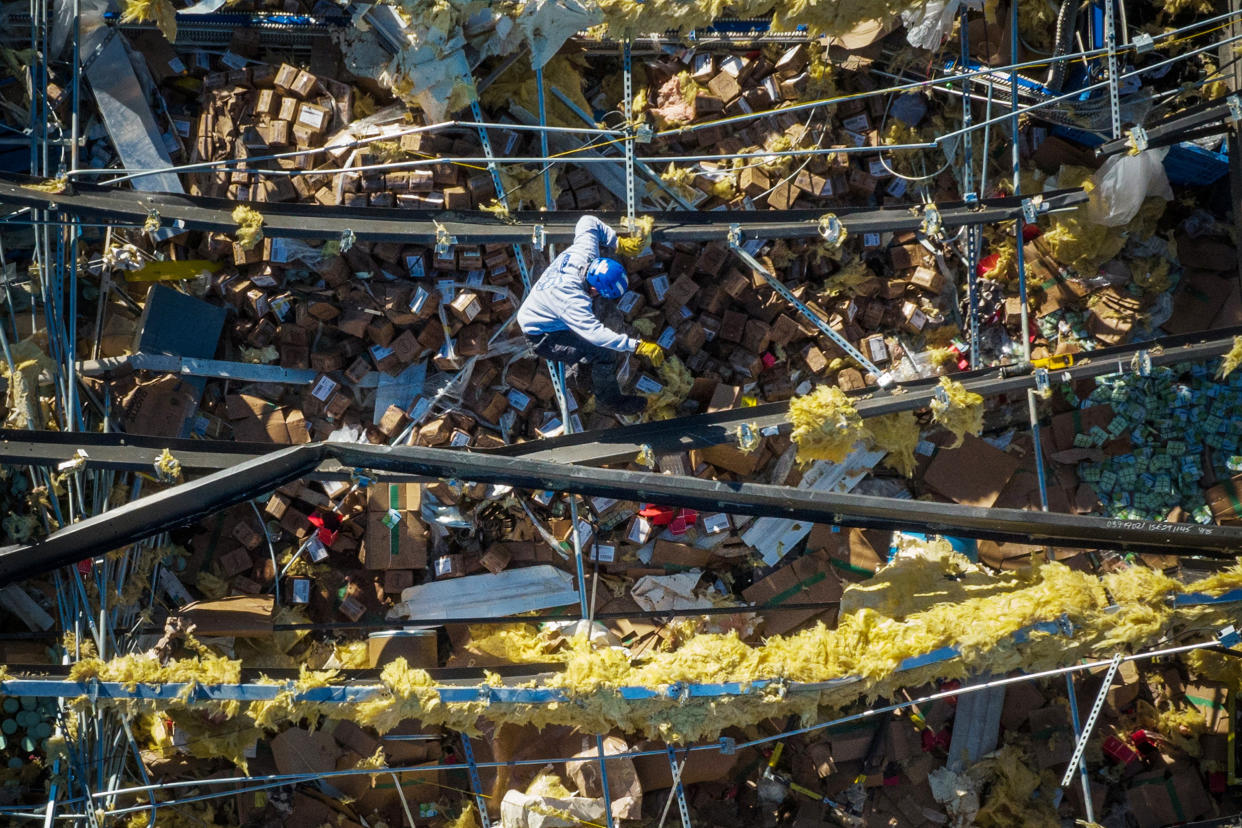 Image: A man searches for victims while climbing past the collapsed roof of the Mayfield Consumer Products candle factory in the aftermath of a tornado in Mayfield, Ky. on Dec. 13, 2021. (Adrees Latif / Reuters)