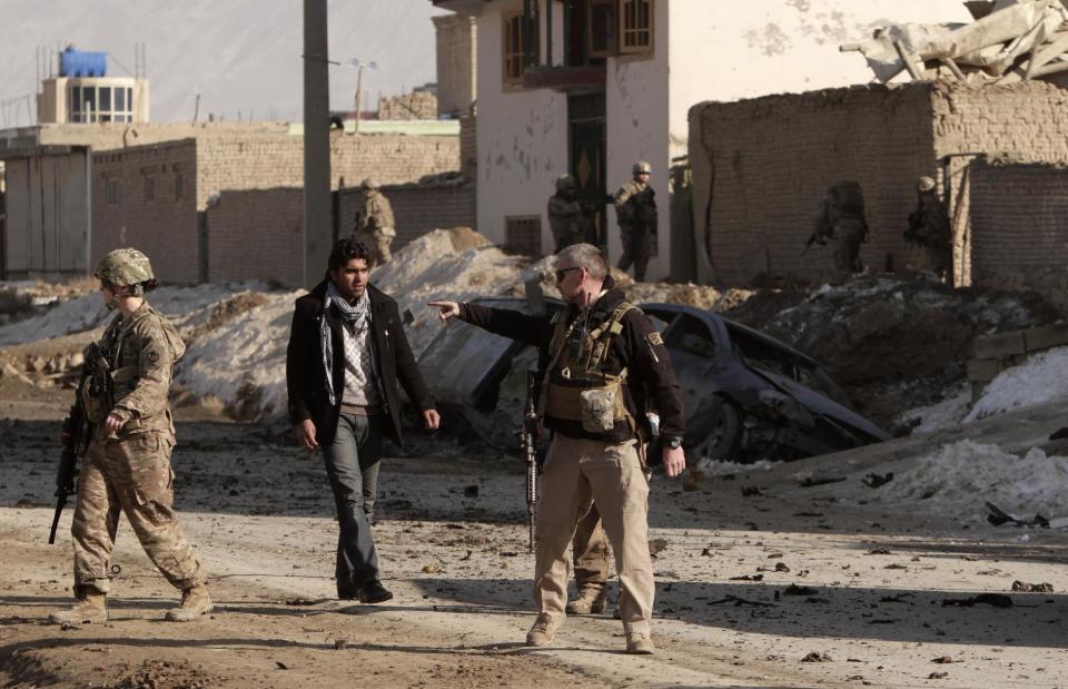 U.S. soldiers secure the site where a suicide attacker rammed a car bomb into a NATO convoy killing two foreign civilian contractors, in the Afghan capital Kabul, Afghanistan, Monday, Feb. 10, 2014. The Islamic militant group Hizb-i-Islami claimed responsibility for the Monday attack in eastern Kabul, saying it would drive all foreign forces from Afghanistan. (AP Photo/Rahmat Gul)