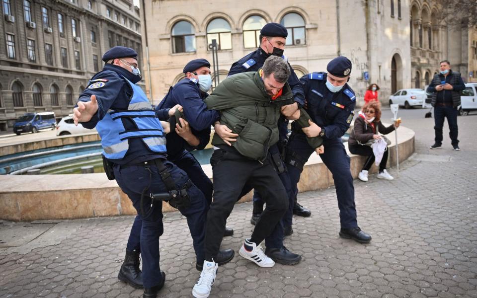 Romanian gendarmes struggle to detain a man during a protest against the newly instated restrictions due to the increasing number of Covid-19 infections. Around 2,000 people take part in a protest and march downtown Bucharest claiming that the restrictions are a limitation of their civil rights. - DANIEL MIHAILESCU/AFP via Getty Images