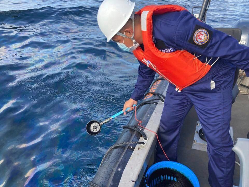 A coast guard collects water samples from an oil spill in the waters off Naujan, Oriental Mindoro, on March 2.