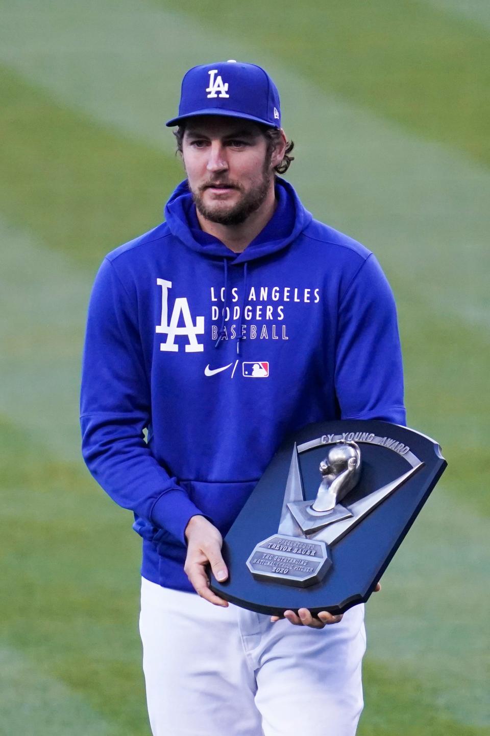 Los Angeles Dodgers pitcher Trevor Bauer holds the 2020 Cy Young Award before a baseball game between the Cincinnati Reds and the Los Angeles Dodgers Tuesday, April 27, 2021, in Los Angeles. He was presented with the award before the game.