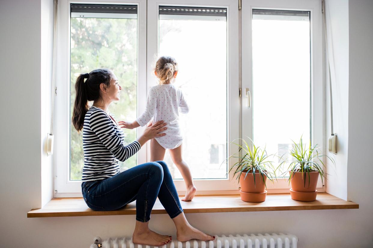 Woman and her child in their home in front of a window