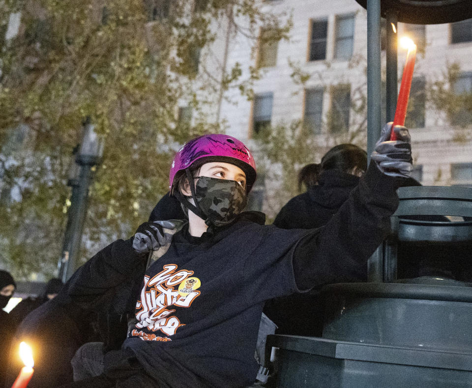 Ashen Blumberg, 13 years old, of San Francisco holds a candle during a protest against police brutality in Oakland, Calif., on Friday, April 16, 2021. (AP Photo/Ethan Swope)