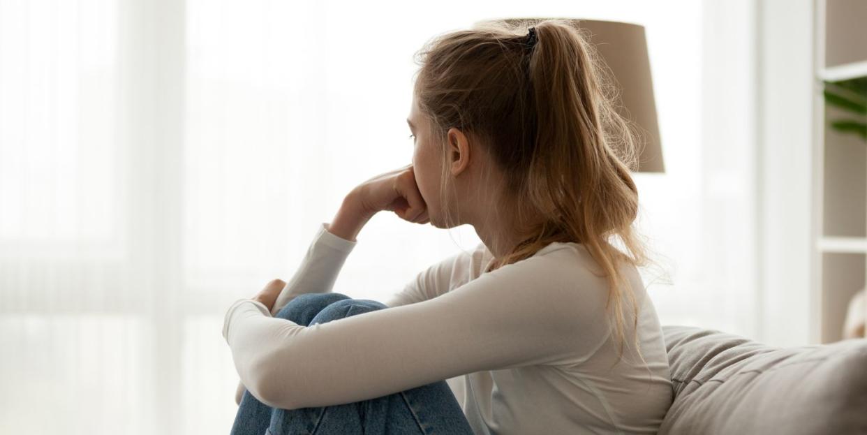 upset woman sitting on couch alone at home