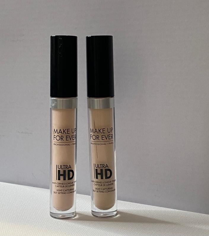 Two light colored concealer with black caps and bold text with 