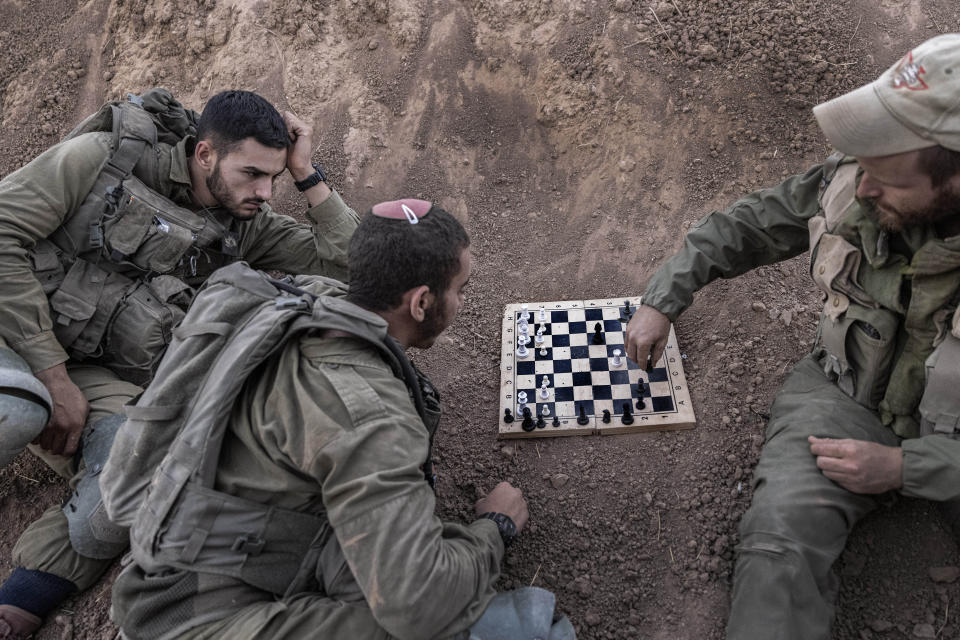 Israeli soldiers play chess at their position near the Israel-Gaza border, Monday, Aug. 16, 2021. Air raid sirens sounded in southern Israel on Monday after a rocket was fired from the Gaza Strip, the first since the 11-day war between Israel and Palestinian militants in May. (AP Photo/Tsafrir Abayov)