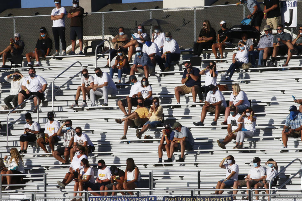 Davis fans sit in the stands during a high school football game against Herriman on Thursday, Aug. 13, 2020, in Herriman, Utah. Utah is among the states going forward with high school football this fall despite concerns about the ongoing COVID-19 pandemic that led other states and many college football conferences to postpone games in hopes of instead playing in the spring. (AP Photo/Rick Bowmer)