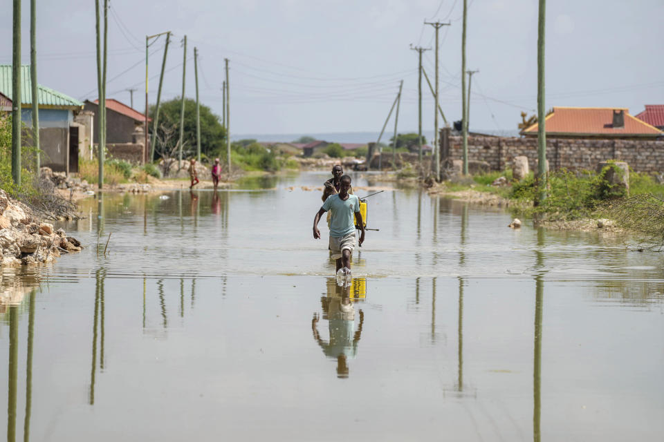 People wade through a section of a road destroyed by floods in Mandera County, Kenya, Wednesday, Dec. 13, 2023. (AP Photo/Brian Inganga)