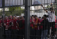A fan climbs on the fence in front of the Stade de France prior the Champions League final soccer match between Liverpool and Real Madrid, in Saint Denis near Paris, Saturday, May 28, 2022. Police have deployed tear gas on supporters waiting in long lines to get into the Stade de France for the Champions League final between Liverpool and Real Madrid that was delayed by 37 minutes while security struggled to cope with the vast crowd and fans climbing over fences. (AP Photo/Christophe Ena)