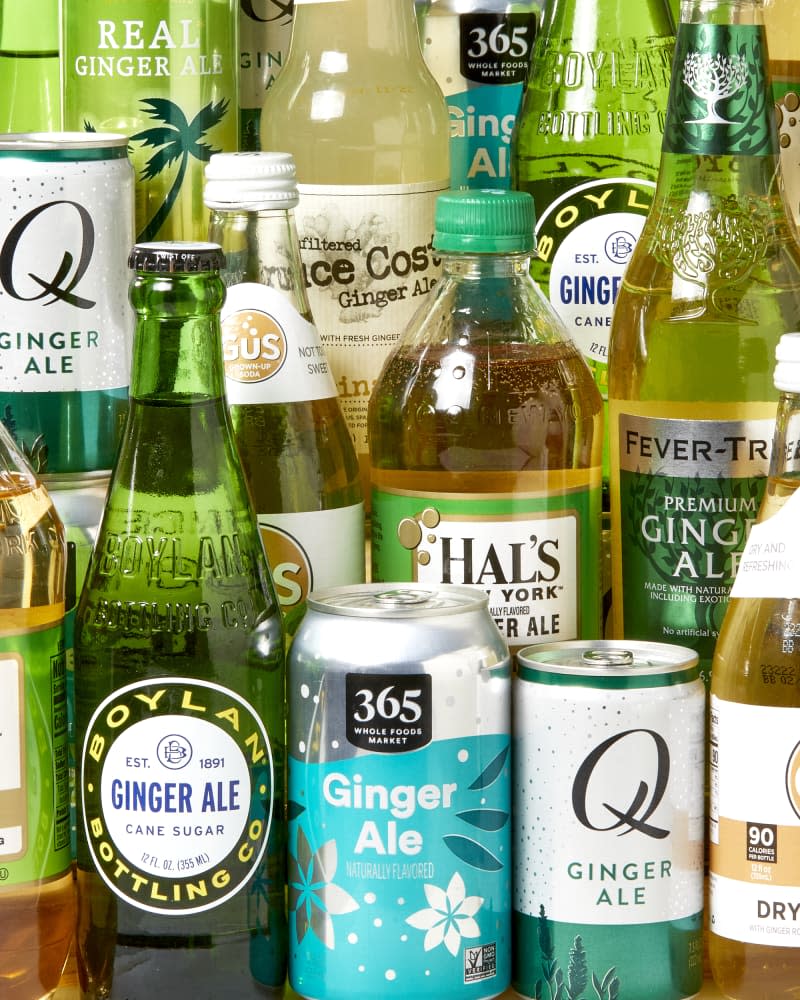 Head on group shot of an assortment of many bottles, cans and brands of ginger ale.