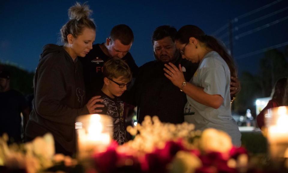 A group of people huddle and say a prayer after a vigil at Texas First Bank in Santa Fe.