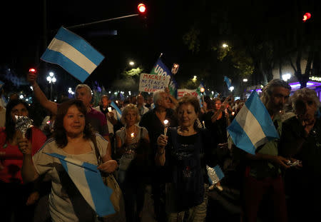 Demonstrators hold candles and wave Argentine national flags during a protest against utility rate hikes in Buenos Aires, Argentina, April 19, 2018. REUTERS/Marcos Brindicci