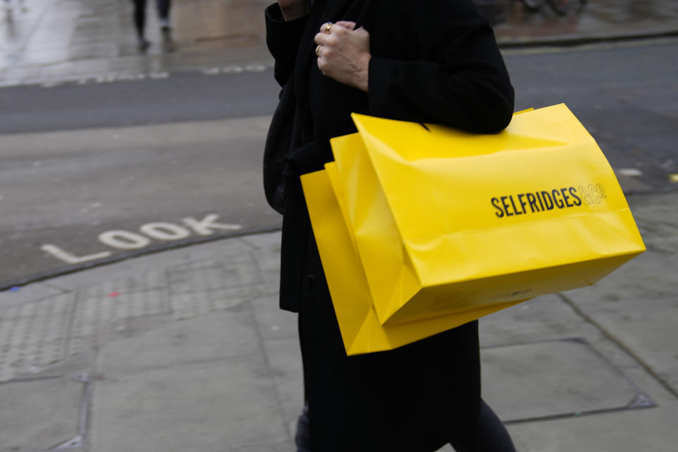 A woman carries a Selfridges bag after leaving the department store in London, Friday, Dec. 24, 2021. Thailand's Central Group and Signa of Austria have confirmed plans to buy luxury British department store chain Selfridges. The deal, reportedly worth 4 billion pounds ($5.4 billion), adds to Central and Signa's collection of posh retailers that includes Rinascente in Italy, Illum in Denmark, Switzerland's Globus and The KaDeWe Group in Germany and Austria. (AP Photo/Alastair Grant)