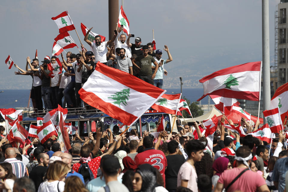 Anti-government protesters chant slogans and wave their national flags at Martyr's Square, in downtown Beirut, Lebanon, Sunday, Oct. 20, 2019. Lebanon is bracing for what many expect to be the largest protests in the fourth day of anti-government demonstrations. Thousands of people of all ages were gathering in Beirut's central square Sunday waving Lebanese flags and chanting the, "people want to bring down the regime." (AP Photo/Hussein Malla)