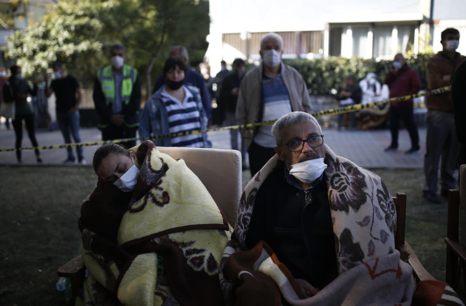 Local residents, staying outdoors for fear of aftershocks, watch as members of rescue services search for survivors in the debris of a collapsed building in Izmir, Turkey, Sunday, Nov. 1, 2020. Rescue teams continue ploughing through concrete blocs and debris of collapsed buildings in Turkey's third largest city in search of survivors of a powerful earthquake that struck Turkey's Aegean coast and north of the Greek island of Samos, Friday Oct. 30, killing dozens Hundreds of others were injured.(AP Photo/Emrah Gurel)