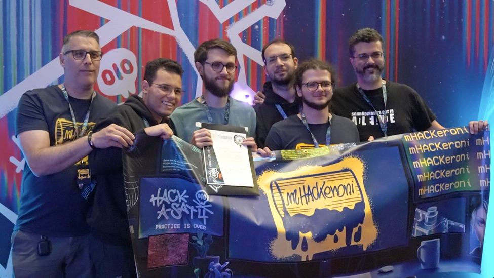  a team of people hold a trophy and a flag that reads "hack-a-sat" 