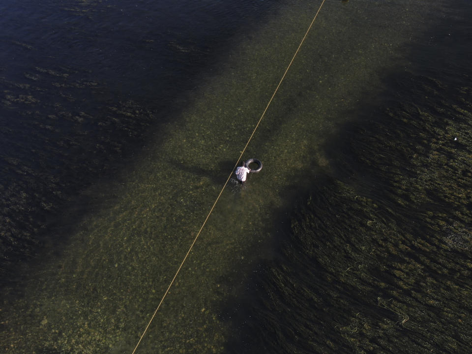 A migrants pushes an inner tube across the Rio Grande river as migrants, many from Haiti, leave Del Rio, Texas, to return to Ciudad Acuna, Mexico, early Wednesday, Sept. 22, 2021, some to avoid possible deportation from the U.S. and others to pick up supplies. (AP Photo/Fernando Llano)