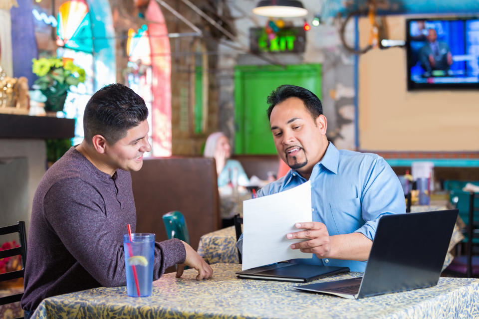 two people sitting at a restaurant looking at paperwork