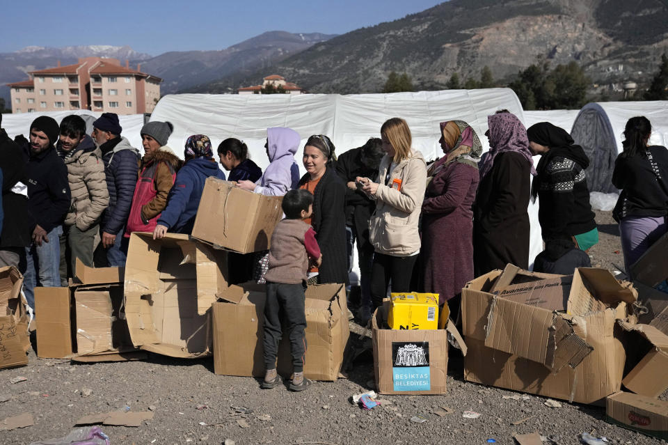 People who lost their houses in the devastating earthquake, lineup to receive aid supplies at a makeshift camp, in Iskenderun city, southern Turkey, Tuesday, Feb. 14, 2023. A convoy of 11 trucks from a United Nations agency crossed into northern Syria from Turkey on Tuesday, just hours after the U.N. and Syrian government reached an agreement to temporarily authorize two new border crossings into the rebel enclave. (AP Photo/Hussein Malla)