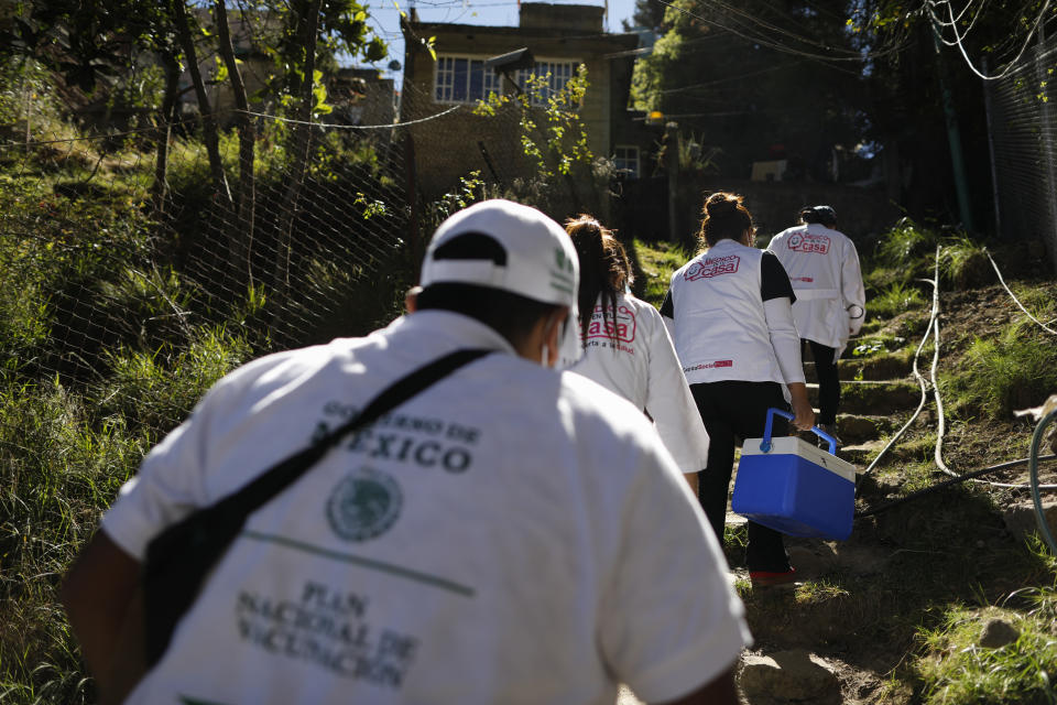 FILE - In this Feb. 18, 2021 file photo, a medical team ascends steps up a hillside to reach the home of Maria del Socorro Fuentes to administer a shot of the AstraZeneca coronavirus vaccine, in rural San Lorenzo Acopilco on the outskirts of Mexico City. As Mexico approaches 200,000 in officially test-confirmed deaths from COVID-19, the real death toll is probably higher due to the country’s extremely low rate of testing. (AP Photo/Rebecca Blackwell, File)