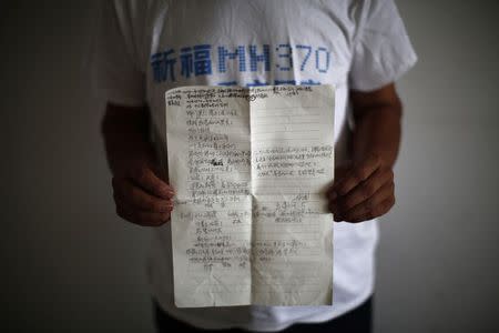 Zhang Yongli, whose daughter Zhang Qi was onboard Malaysia Airlines Flight MH370 which disappeared on March 8, 2014 shows a note featuring a poem which Zhang wrote for his daughter, during an interview with Reuters in Beijing July 22, 2014. REUTERS/Kim Kyung-Hoon/Files