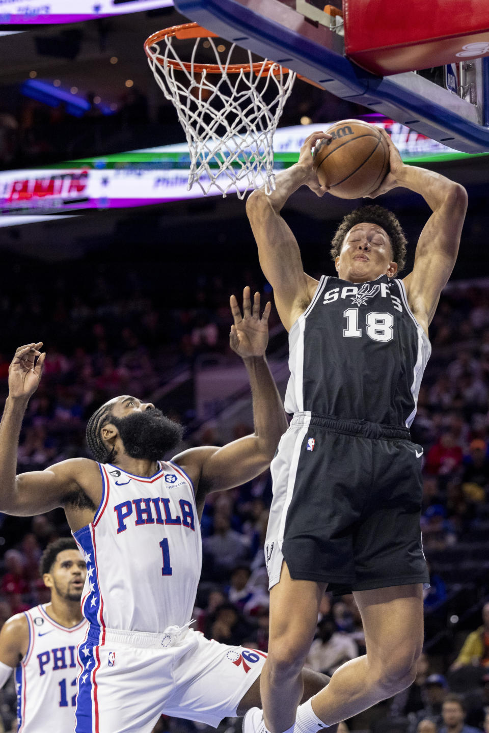 San Antonio Spurs forward Isaiah Roby (18) grabs a rebound away from Philadelphia 76ers guard James Harden (1) in the first half of an NBA basketball game, Saturday, Oct. 22, 2022, in Philadelphia. (AP Photo/Laurence Kesterson)