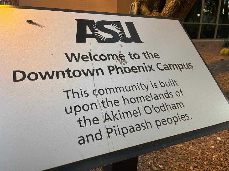 An Indigenous land acknowledgment plaque on Arizona State University's downtown Phoenix campus. The sign is near a pedestrian walkway between the Watts College of Public Service and Community Solutions and the Walter Cronkite School of Journalism and Mass Communication.