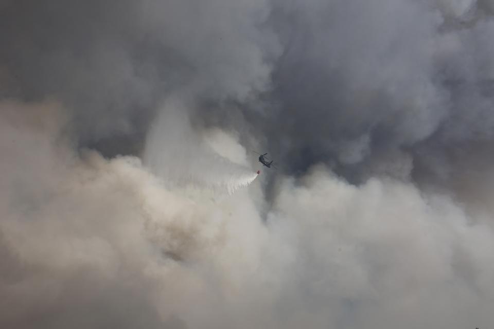 A military helicopter drops water over a wildfire in Voula suburb, in southern Athens, Greece, Saturday, June 4, 2022. A combination of hot, dry weather and strong winds makes Greece vulnerable to wildfire outbreaks every summer. (AP Photo/Yorgos Karahalis)