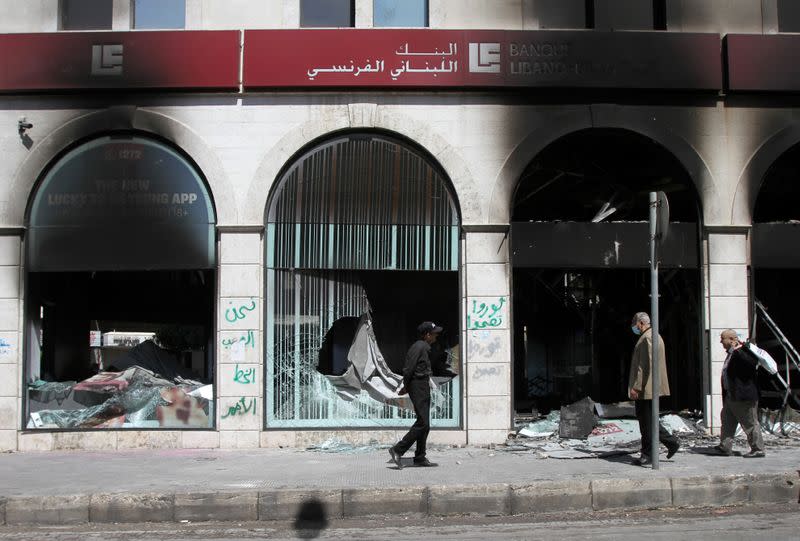 People walk past burned-out bank facade that was set ablaze during unrest overnight in Tripoli