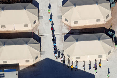 Immigrant children, many of whom have been separated from their parents under a new "zero tolerance" policy by the Trump administration, walk in single file between tents in their compound next to the Mexican border in Tornillo, Texas, U.S. June 18, 2018. REUTERS/Mike Blake