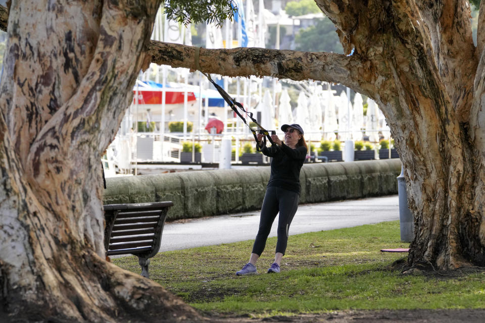 A woman workouts in a park in the eastern suburbs of Sydney Tuesday, Sept. 14, 2021. Personal trainers have turned a waterfront park at Sydney’s Rushcutters Bay into an outdoor gym to get around pandemic lockdown restrictions. (AP Photo/Mark Baker)