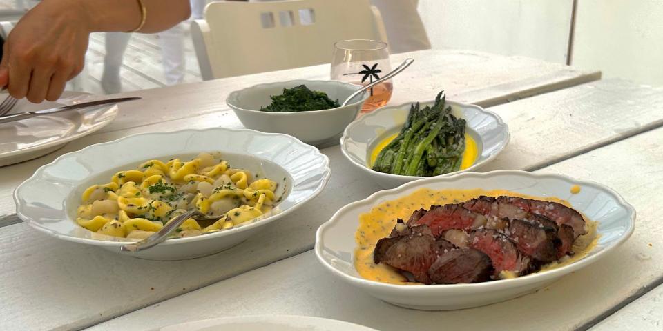 asparagus, steak, and pasta on plates on white wood table