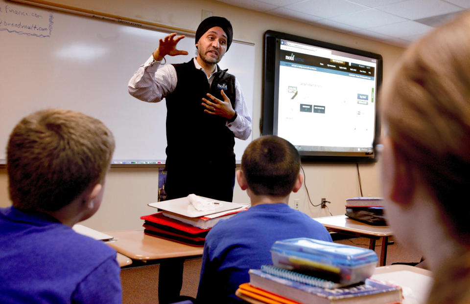 In this March 18, 2014 photo Motif Investing founder Hardeep Walia talks with sixth grade students at Oak Grove Middle School in Fargo, North Dakota. Sixth grade teacher Dave Carlson started a competition between regular and advance math classes at Oak Grove and registered his students with Motif Investing, a company that enables customers to buy baskets of stocks. In the end, Carlson’s regular math class yielded a nearly 22 percent gain and trounced every university club participating in a contest that was held at the same time. (AP Photo/Bruce Crummy)