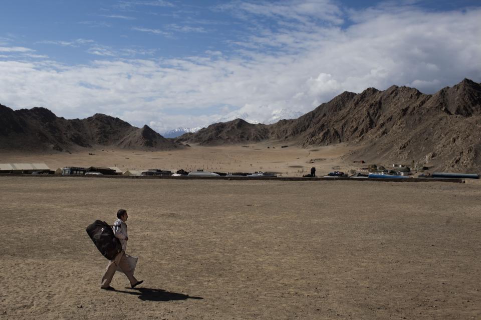 FILE - In this May 6, 2014 file photo, an Indian election worker walks with a voting machine on his way to a nearby polling station on the eve of the eighth phase of voting for the Indian parliamentary elections in Leh, near the India-China border in Ladakh, India. India’s surprise move in August 2019, to carve out the sparsely populated region of Ladakh from the state of Jammu and Kashmir and make it into a territory directly controlled by New Delhi has been met with protests in Kargil, a Muslim-majority border city in Ladakh that identifies culturally with Kashmir, suggesting that the Hindu nationalist-led government’s plan to redraw the country’s political map will be far from easy. The people of Kargil have opposed Ladakh’s decades-long demand to be severed from Kashmir. The friction between the two districts has occasionally sparked clashes between the two communities. Despite Kargil’s opposition, Ladakh’s elected representative to the Indian Parliament described the mood in the region as celebratory. (AP Photo/Bernat Armangue, File)