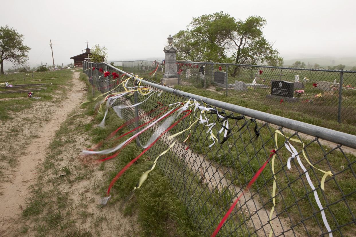 Wounded Knee, South Dakota, U.S.A. - May 26, 2013: On Memorial Day weekend, fog rolls over hills on the Lakota Pine Ridge Indian Reservation as wind blows colorful ribbons like prayer flags surrounding the tall marble cemetery memorial marking the Wounded