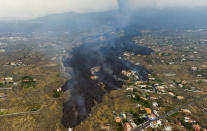 FILE - In this Tuesday, Sept. 21, 2021 file photo, lava from a volcano eruption flows destroying houses on the island of La Palma in the Canaries, Spain. A long-dormant volcano on a small Spanish island in the Atlantic Ocean erupted on Sunday Sept. 19, 2021, forcing the evacuation of thousands of people. Huge plumes of black-and-white smoke shot out from a volcanic ridge where scientists had been monitoring the accumulation of molten lava below the surface. (AP Photo/Emilio Morenatti, File)