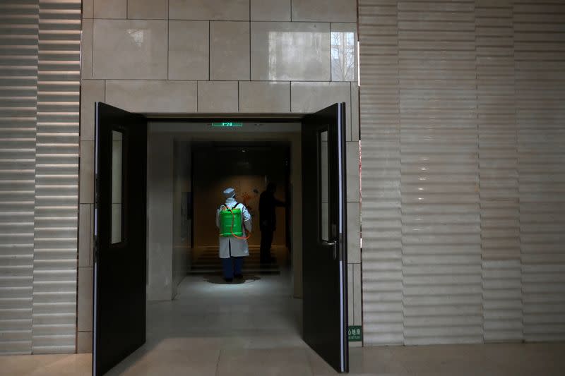 Worker Wang Fu wearing a face mask sprays disinfectant at an apartment of a residential compound, as the country is hit by an outbreak of the novel coronavirus, in Beijing