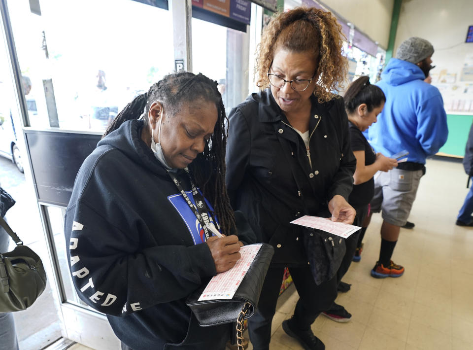 Oqulla Jackson, left, and Arlene Johnson, right, fill out Powerball lottery forms while waiting to purchase lottery tickets at Lichine's Liquor & Deli in Sacramento, Calif., Monday, Oct. 31, 2022. The jackpot for Monday night's drawing soared to $1 billion after no one matched all six numbers in Saturday night's drawing. It's the fifth-largest lottery jackpot in U.S. history. (AP Photo/Rich Pedroncelli)